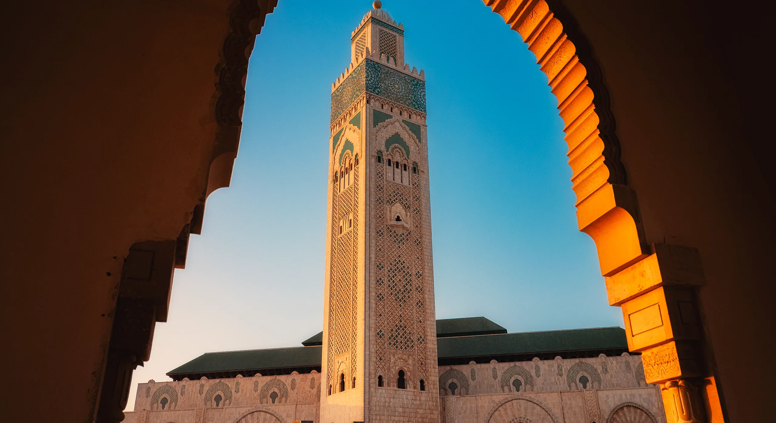The minaret of the Hassan II Mosque in Casablanca framed by an arch at dusk