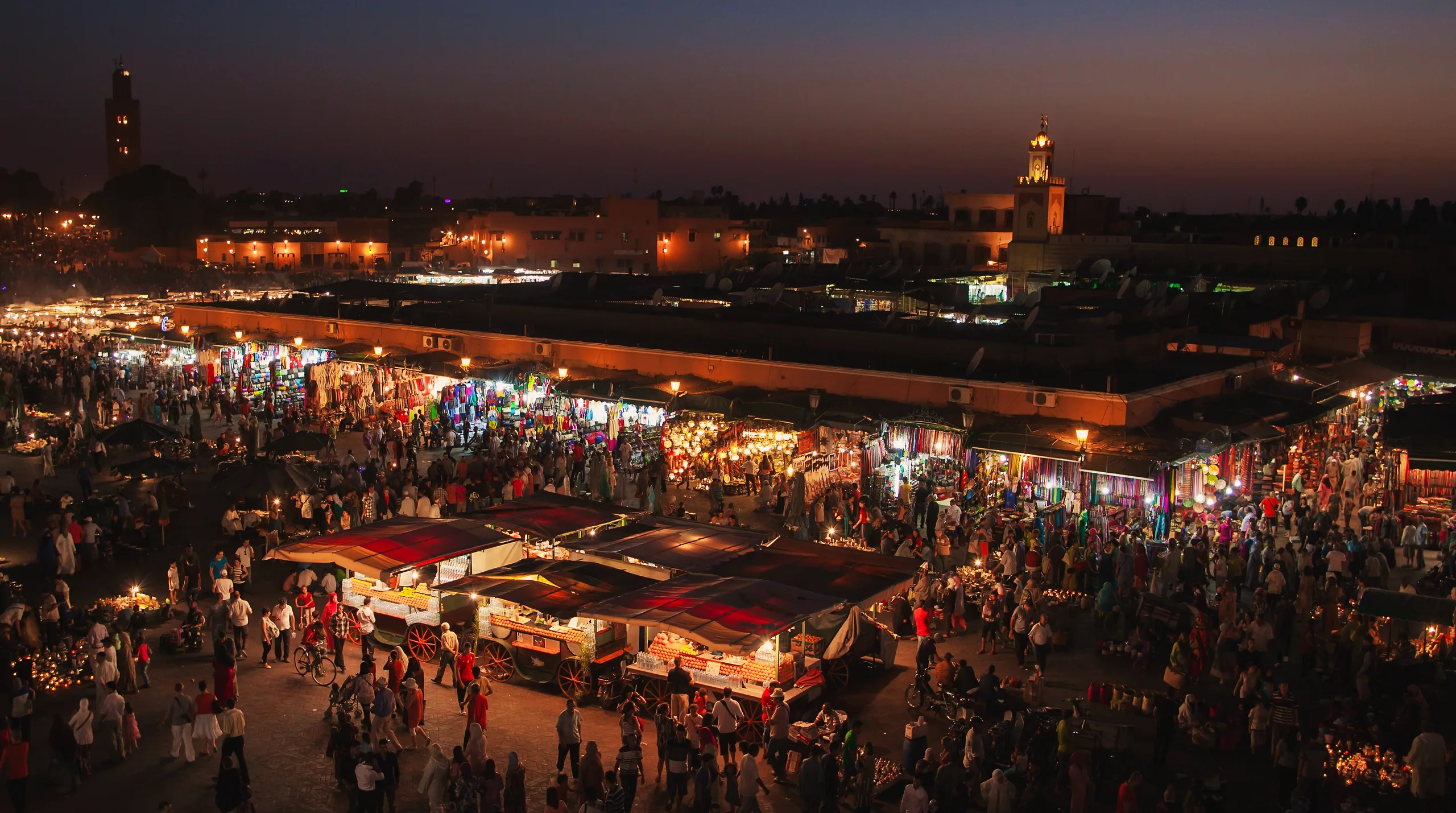 Food stalls lit up on Jemaa el-Fna square at night, smoke rising from the grills